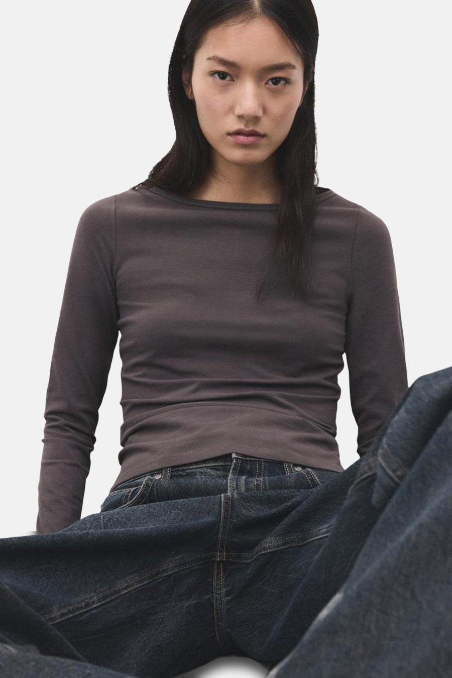 T-shirt gris à manches longues de MANGO, porté avec un jean foncé et un fond uni.