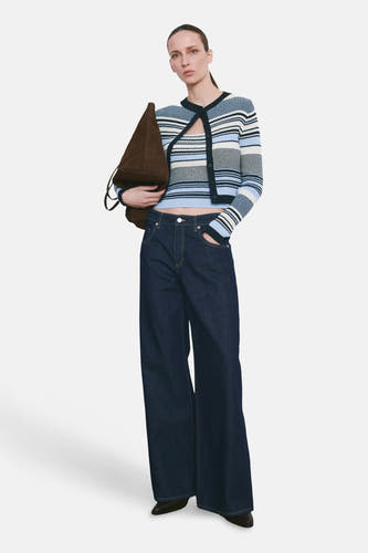 Gilet multicolore de MANGO, porté avec un cardigan rayé et un jean ample.