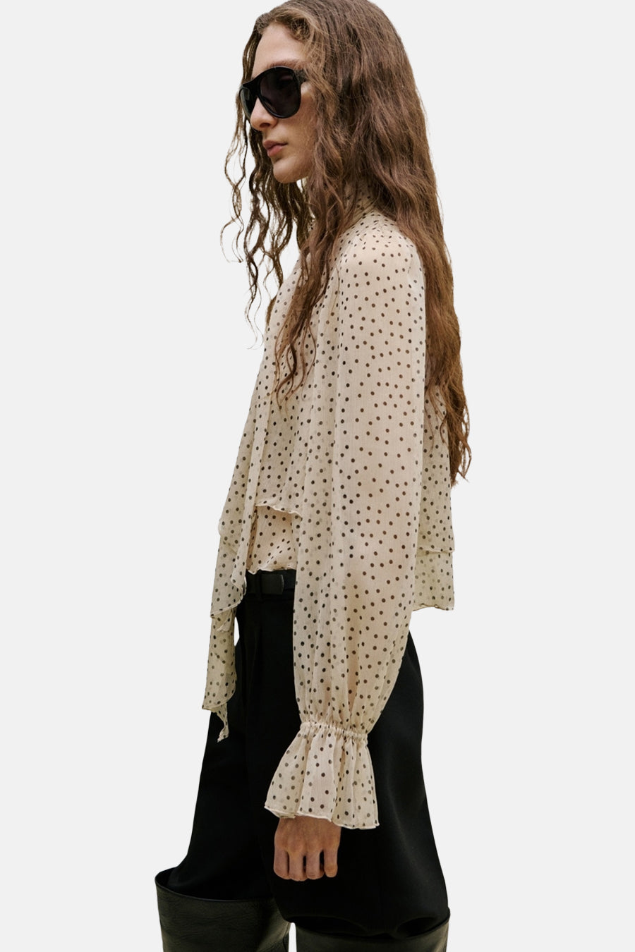 Beige blouse van MANGO met stippenpatroon, lange mouwen met ruches en strikdetail aan de hals, in zij aanzicht.