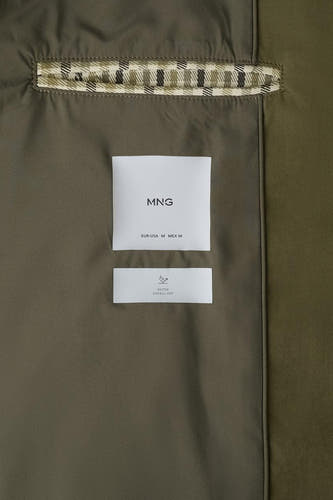 Long manteau kaki de MANGO, avec étiquette visiblement déperlante et détail à carreaux au col.