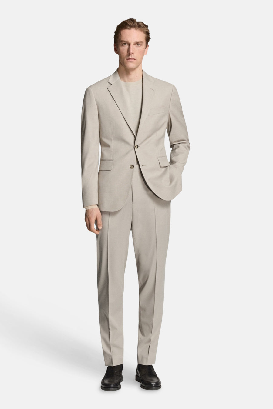 Blazer beige de MANGO, avec une fermeture à boutons et des poches, combiné avec un pantalon assorti et un T-shirt de la même couleur.