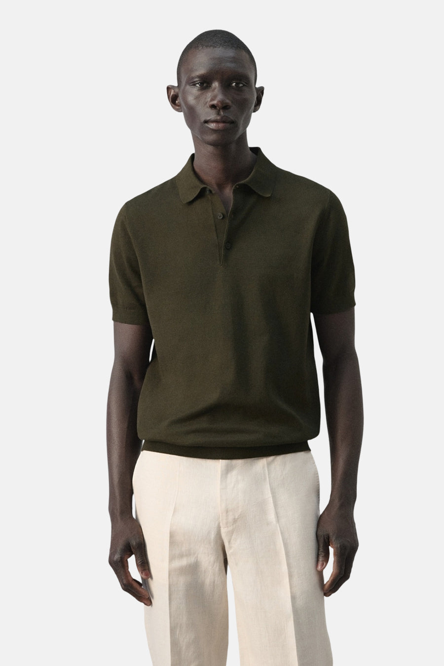 Polo verte MANGO de couleur verte, vue de dos, combinée avec un pantalon clair.