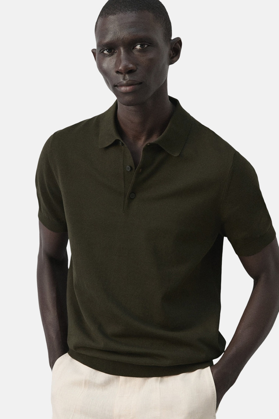 Polo verte MANGO de couleur verte, à manches courtes et avec une fermeture à boutons, portée avec un pantalon clair.