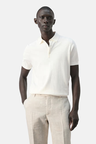 Polo blanche de MANGO, vue de dos, portée avec un pantalon en lin.