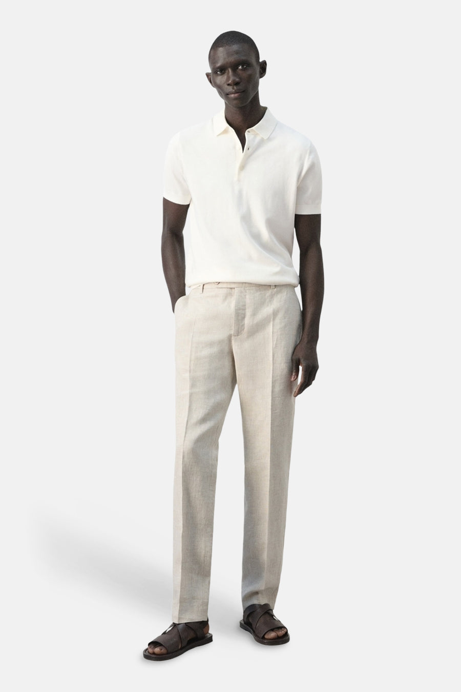 Polo blanche de MANGO, à manches courtes et fermeture boutonnée, combinée avec un pantalon en lin et des sandales en cuir.