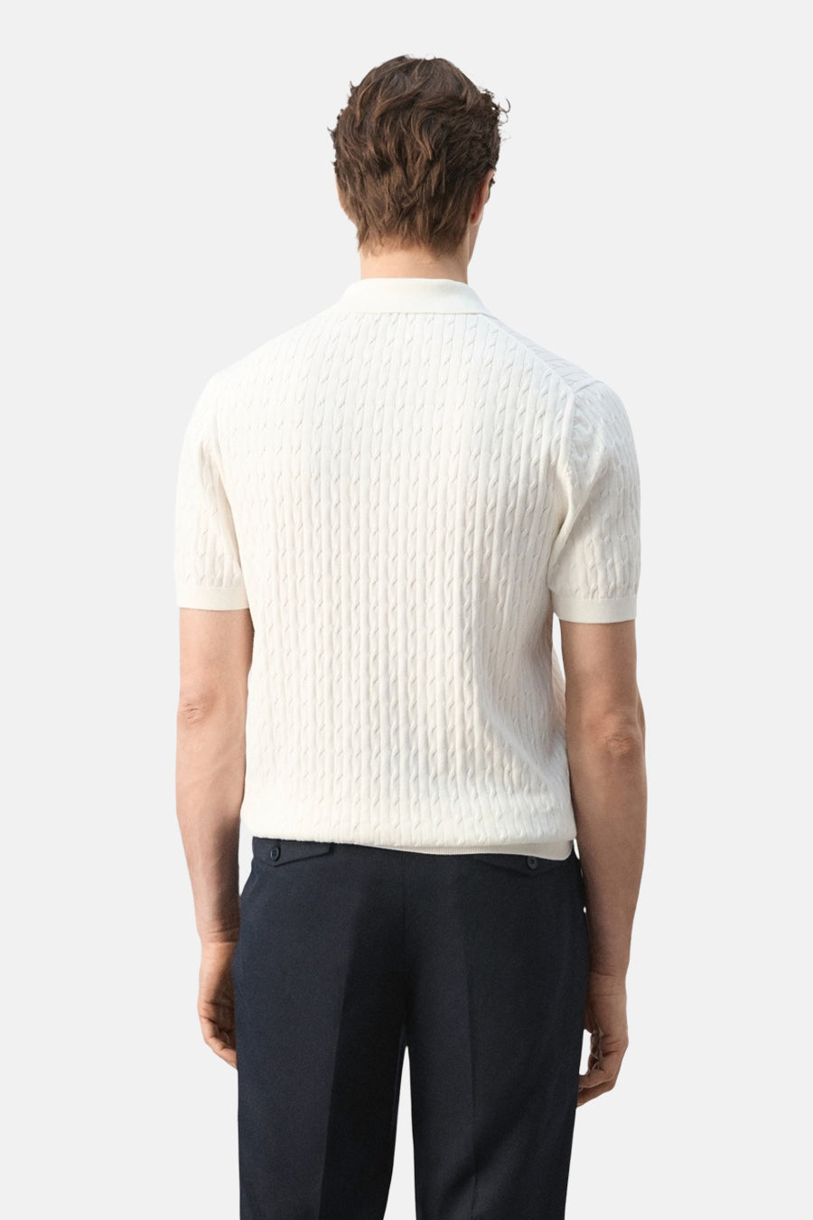 Witte polo van MANGO met korte mouwen en een kabelpatroon op de achterkant, gecombineerd met donkere broek.