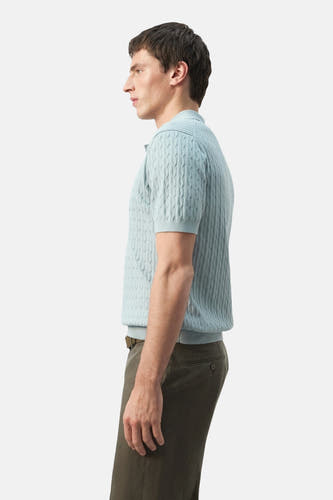 Polo bleu MANGO à motif torsadé et manches courtes, vue de profil, associée à un pantalon vert olive.