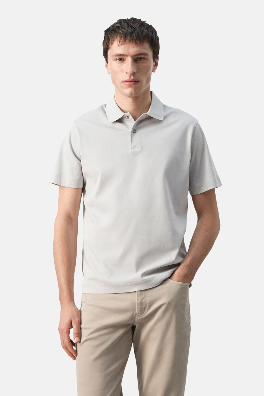 Polo grise de MANGO, vue de dos, à manches courtes et associée à un pantalon beige.