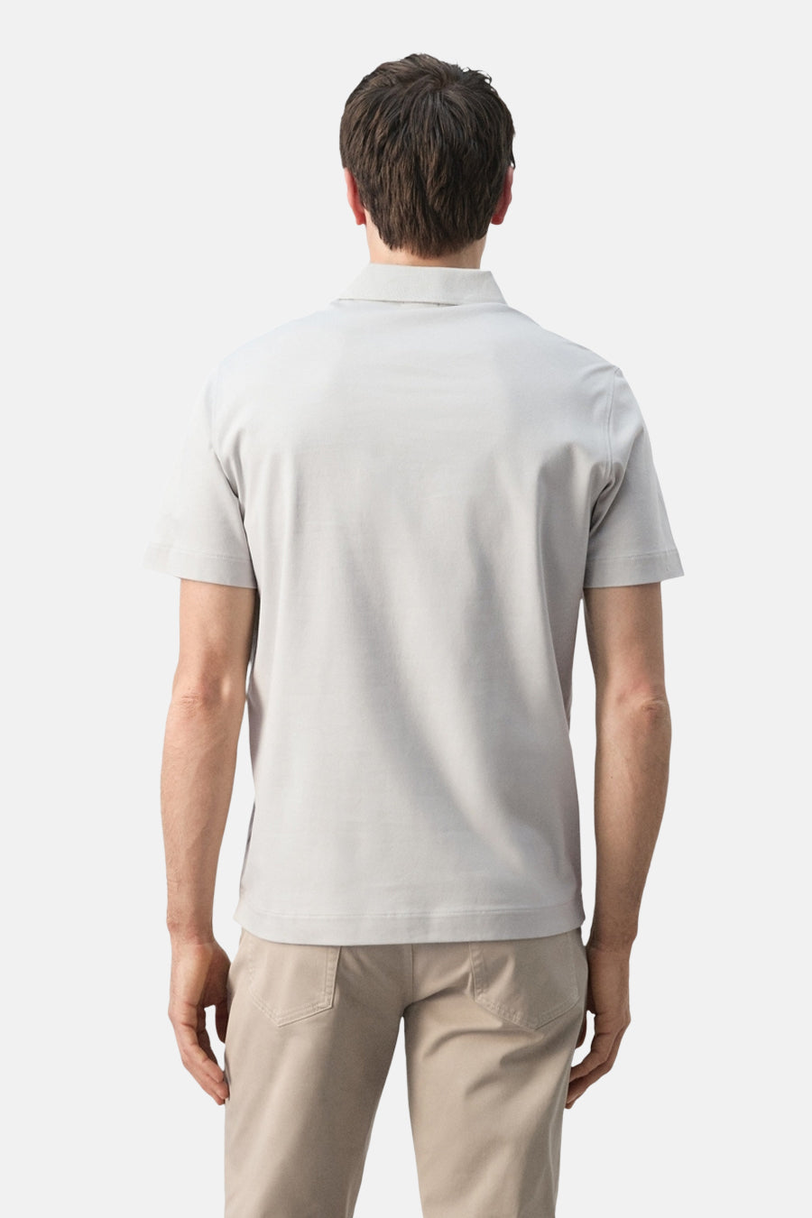 Grijs poloshirt van MANGO, gezien van achteren, met korte mouwen en gecombineerd met beige broek.
