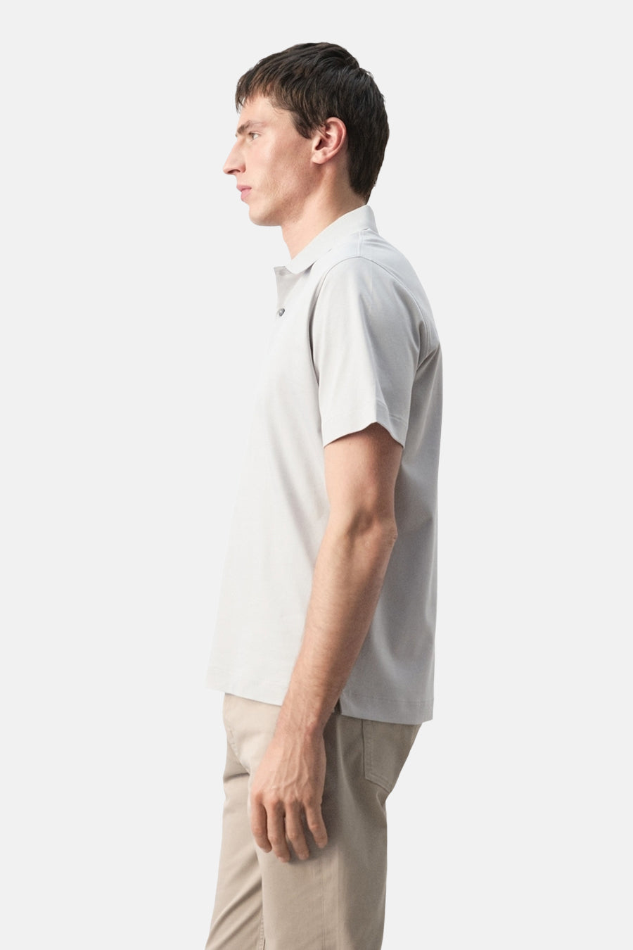 Polo grise de MANGO, portée de profil avec un pantalon beige.