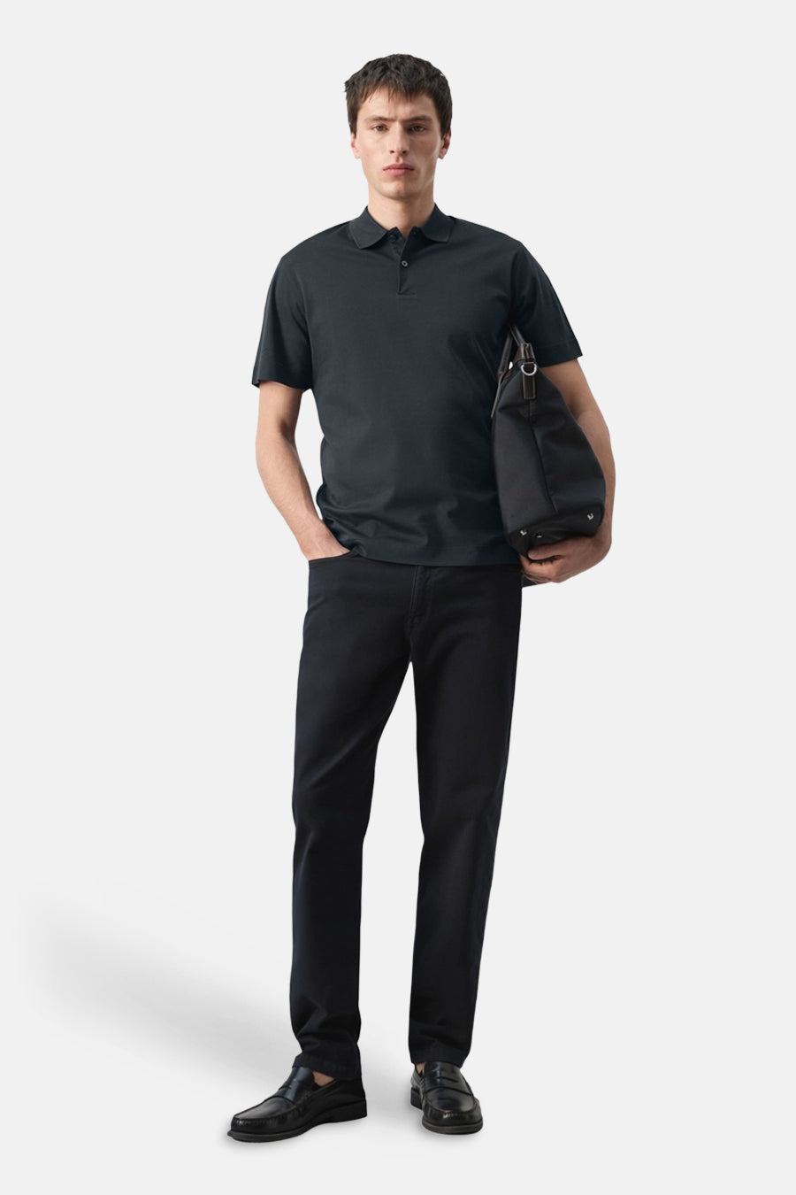 Polo bleue de MANGO, portée avec un pantalon noir, des mocassins et un sac noir.
