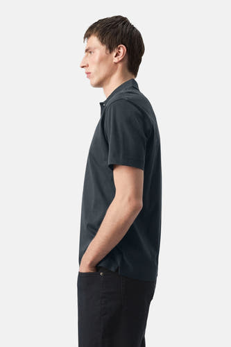Polo bleu de MANGO, portée de profil avec un pantalon foncé.