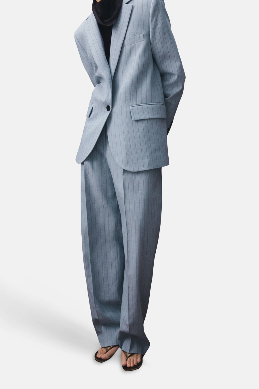 Blazer bleu MANGO à rayures craie et poches, porté avec un pantalon assorti et des sandales.