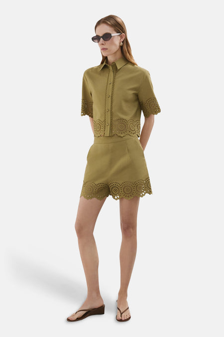 Blouse courte kaki de MANGO avec broderie ajourée circulaire et ourlets festonnés, portée en ensemble.