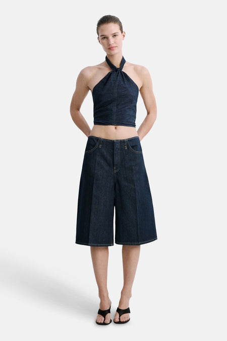 Haut licou en denim bleu foncé de MANGO, associée à un bermuda assorti et des sandales noires.
