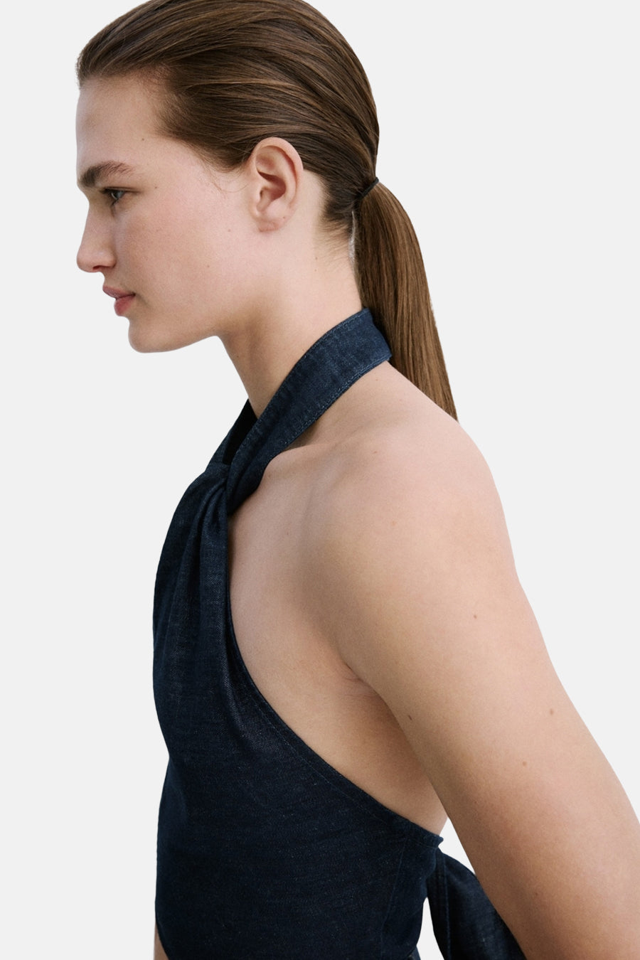 Haut en jean bleu marine de MANGO avec col licou torsadé, sans manches, profil latéral.