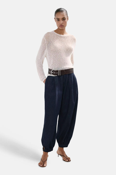 Jeans en denim bleu marine SOUFFLE de MANGO, coupe ample avec chevilles élastiques, combinées avec un pull en maille et une ceinture.