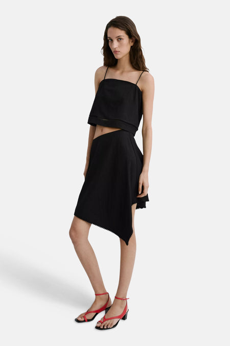 Jupe noire MANGO à coupe asymétrique et ourlet festonné, portée par un mannequin.