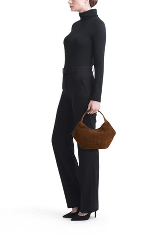 Sac à main hobo en daim marron de MANGO, porté par un mannequin en vêtements noirs.