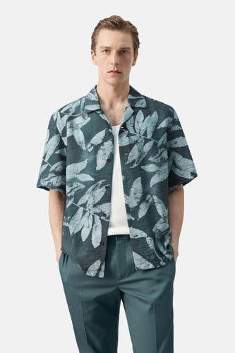 Chemise structurée à manches courtes de couleur vert foncé avec motif à feuilles bleu clair de MANGO, vue de dos sur un homme.