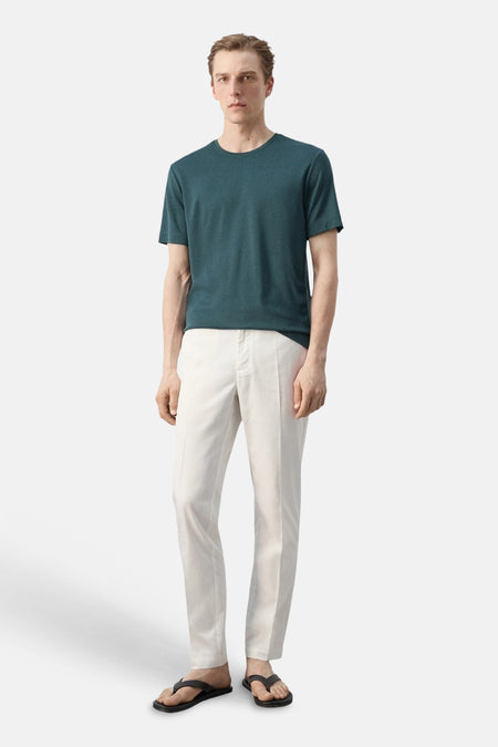 T-shirt vert à manches courtes de MANGO, avec col rond, combiné avec un pantalon clair et des tongs noires.