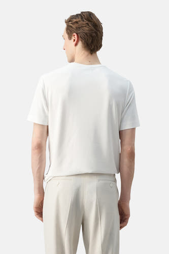 T-shirt blanc à manches courtes de MANGO, porté à l'envers par un homme avec un pantalon beige.
