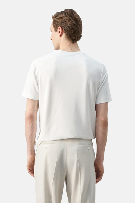 T-shirt blanc à manches courtes de MANGO, porté à l'envers par un homme avec un pantalon beige.