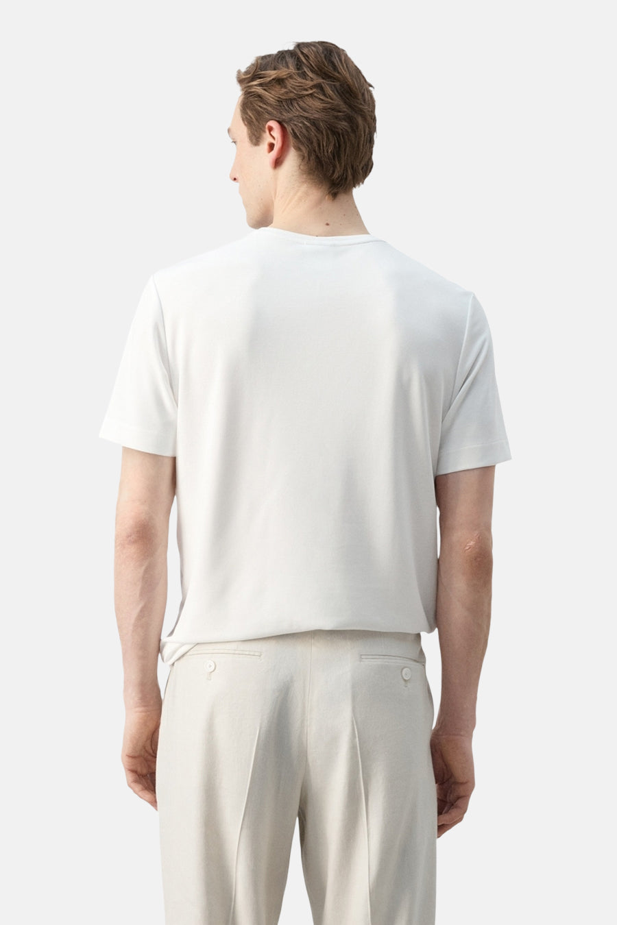 T-shirt blanc à manches courtes de MANGO, porté à l'envers par un homme avec un pantalon beige.