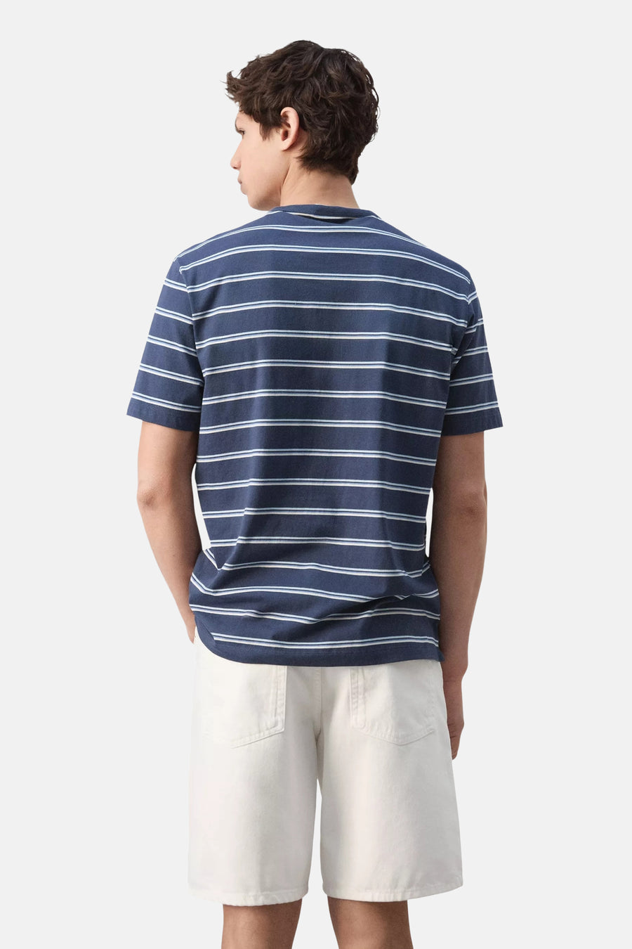 Blauw T-shirt van MANGO, gestreept met wit en lichtblauw, achterkant van een man die witte shorts draagt.
