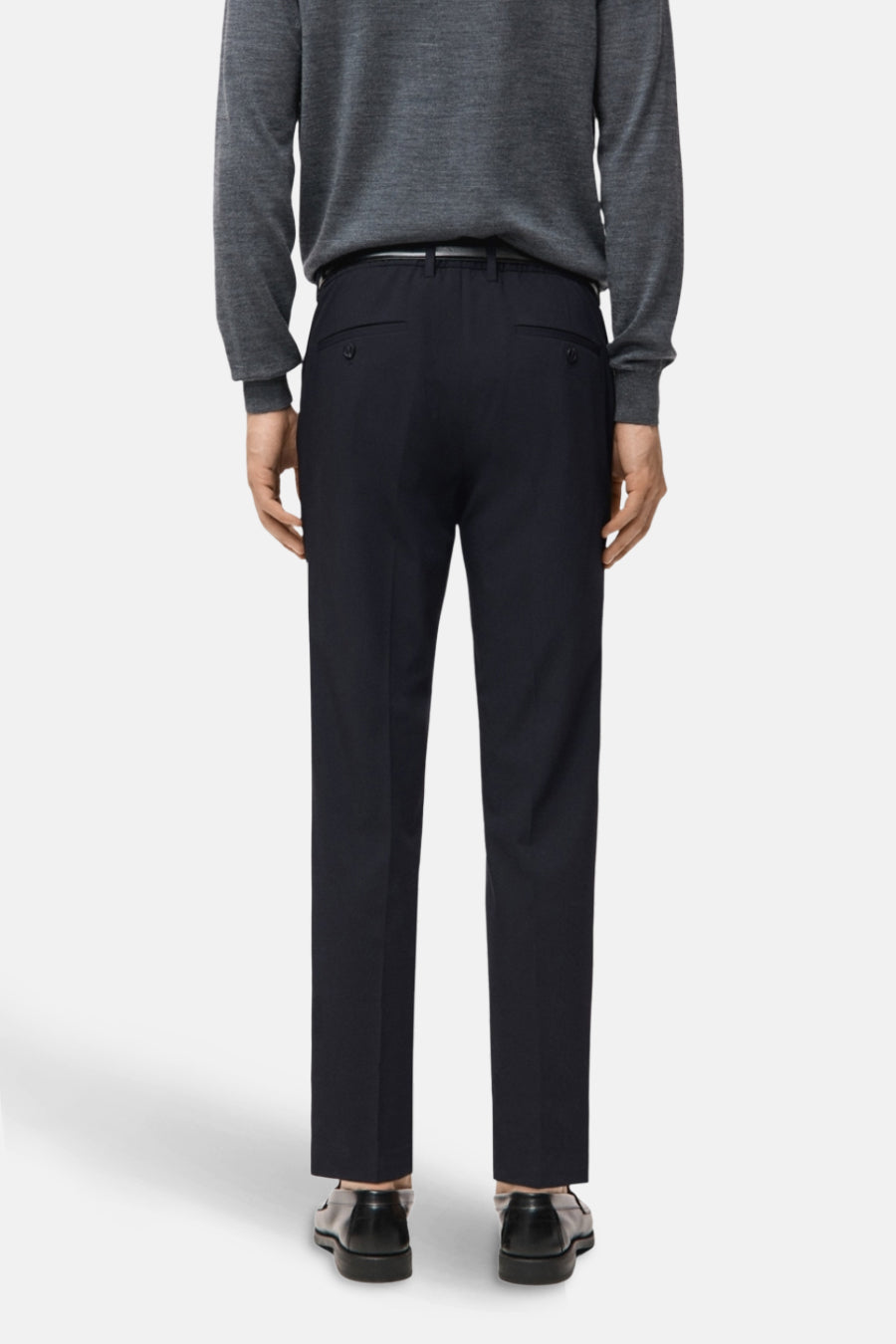 Blauwe chino van MANGO, gezien van achteren, gecombineerd met een grijze trui en zwarte schoenen.
