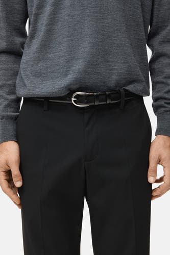 Chino noir de MANGO, associé à une chemise grise et un ceinture noire avec boucle argentée.