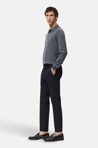 Jean bleu de MANGO, avec une ceinture noire, associé à une polo grise et des loafers en cuir noirs.