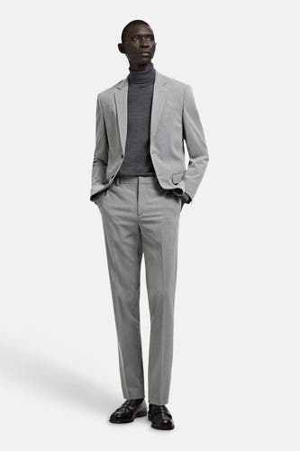 Blazer grise de MANGO, portée avec un col roulé gris et un pantalon assorti, combinée avec des chaussures noires.