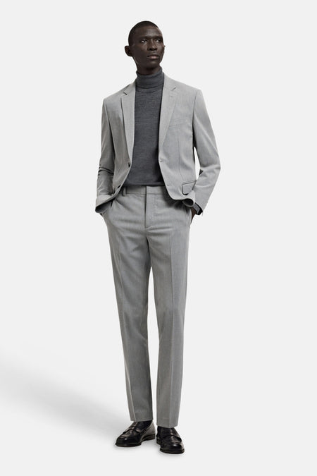 Blazer grise de MANGO, portée avec un col roulé gris et un pantalon assorti, combinée avec des chaussures noires.