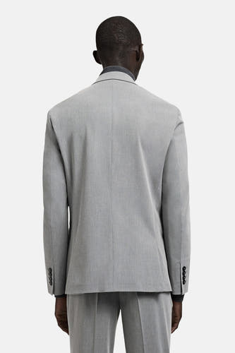 Blazer grise de MANGO, vue de dos, avec des boutons foncés aux poignets et une texture subtile.