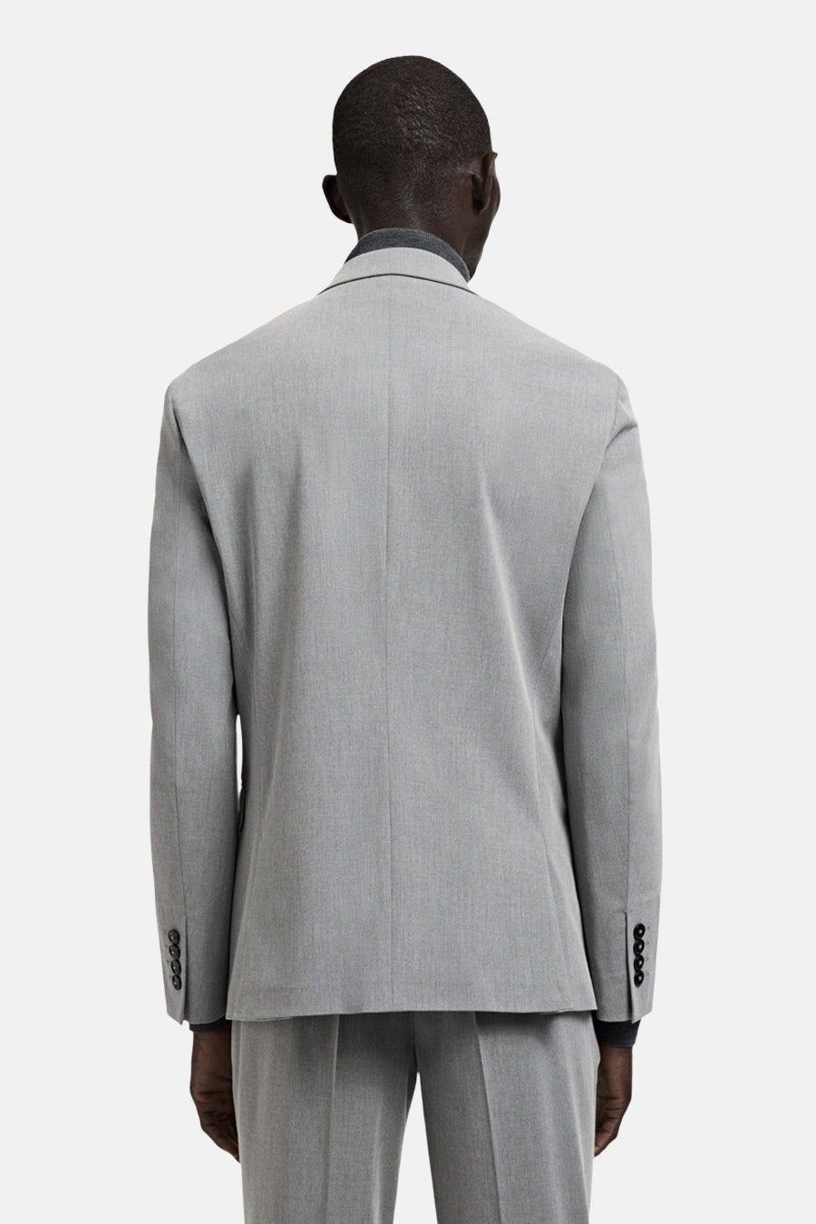 Blazer grise de MANGO, vue de dos, avec des boutons foncés aux poignets et une texture subtile.