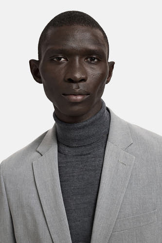 Blazer grise de MANGO, portée sur un pull à col roulé gris.