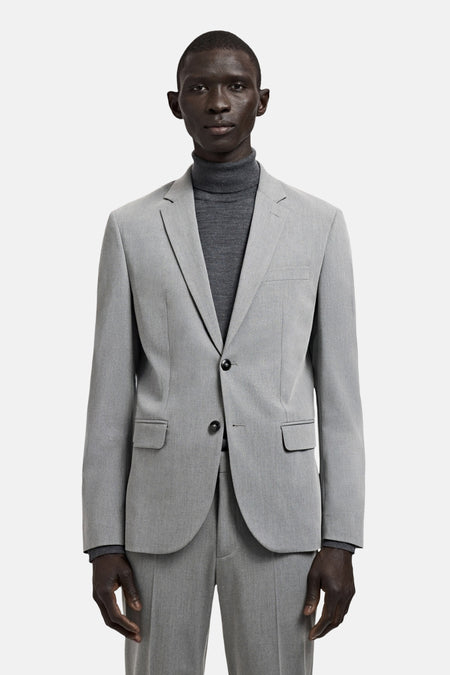 Blazer grise de MANGO, vue de profil, avec des manches longues et un col roulé gris en dessous.