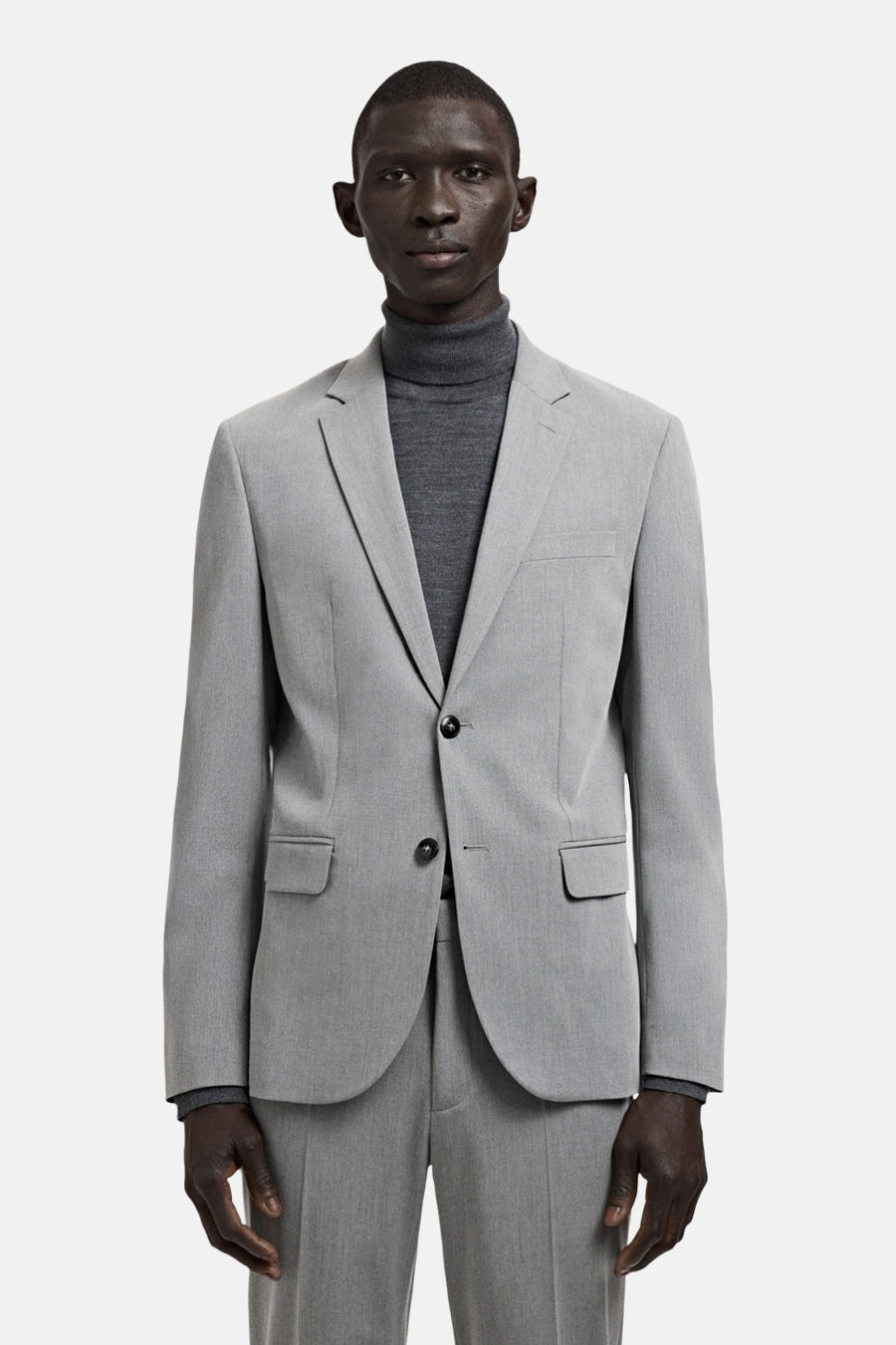 Blazer grise de MANGO, vue de profil, avec des manches longues et un col roulé gris en dessous.
