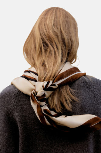 Chapeau d'été multicolore de MANGO, noué autour du cou, porté avec un pull gris.