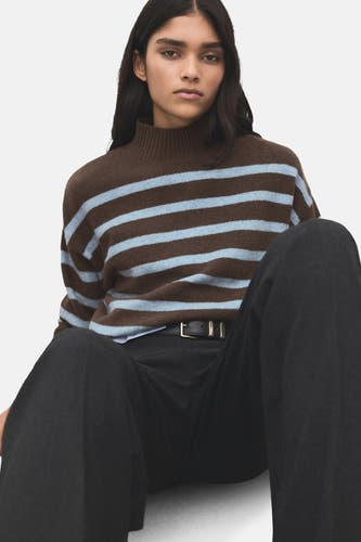 Sweat-shirt multicolore à col rond de MANGO, avec des rayures bleues horizontales, porté avec un pantalon noir et une ceinture.