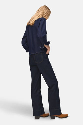 Donkerblauw denim overhemd met lange mouwen van MANGO, gezien van achteren, met een bijpassende donkere denim broek en bruine laarzen.