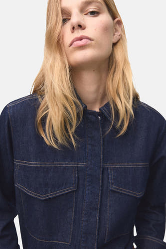 Chemise en denim bleu marine à manches longues de MANGO, avec des poches droites et des surpiqures contrastantes.