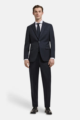 Chemise blanche à manches longues de MANGO, portée sous un costume bleu foncé avec cravate et chaussures noires.