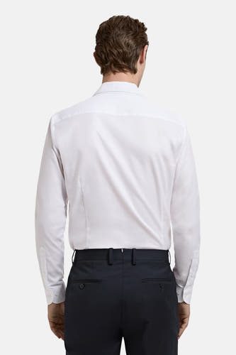 Chemise blanche à manches longues de MANGO, vue de dos, associée à un pantalon foncé.