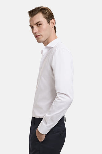 Chemise blanche à manches longues de MANGO, avec un col classique et portée avec un pantalon foncé.