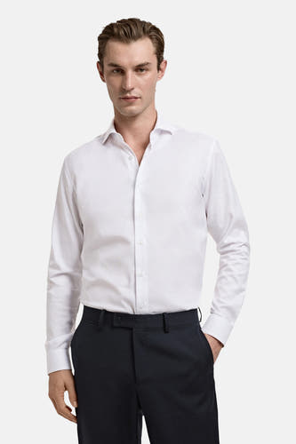 Chemise blanche à manches longues de MANGO, portée avec un pantalon foncé.