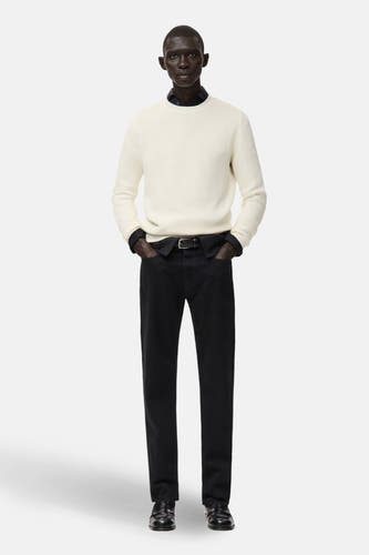 T-shirt écru avec col rond de MANGO, associé à des jeans noirs et des chaussures en cuir.