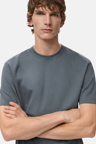 T-shirt bleu à manches courtes de MANGO, avec des bras croisés d'un modèle.