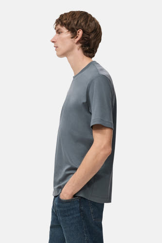 T-shirt bleu à manches courtes de MANGO, vu en profil avec un modèle en jeans bleus.